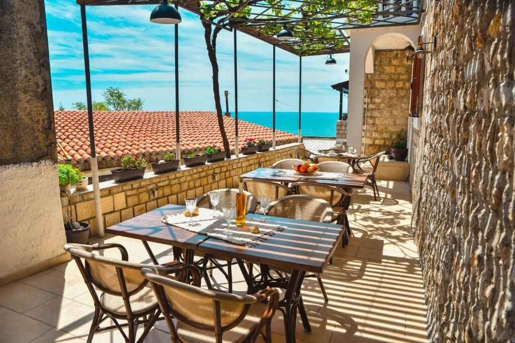 Shaded stone terrace with dining tables and a view of the Adriatic